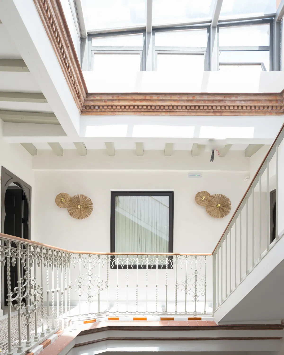 Patio interior con montera acristalada y ventanas de aluminio en un edificio histórico