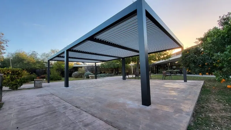 Pérgola bioclimática de aluminio en un jardín al atardecer