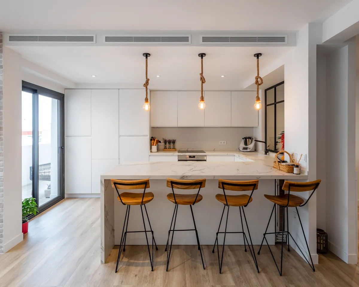Cocina abierta con correderas de aluminio negro hacia la terraza