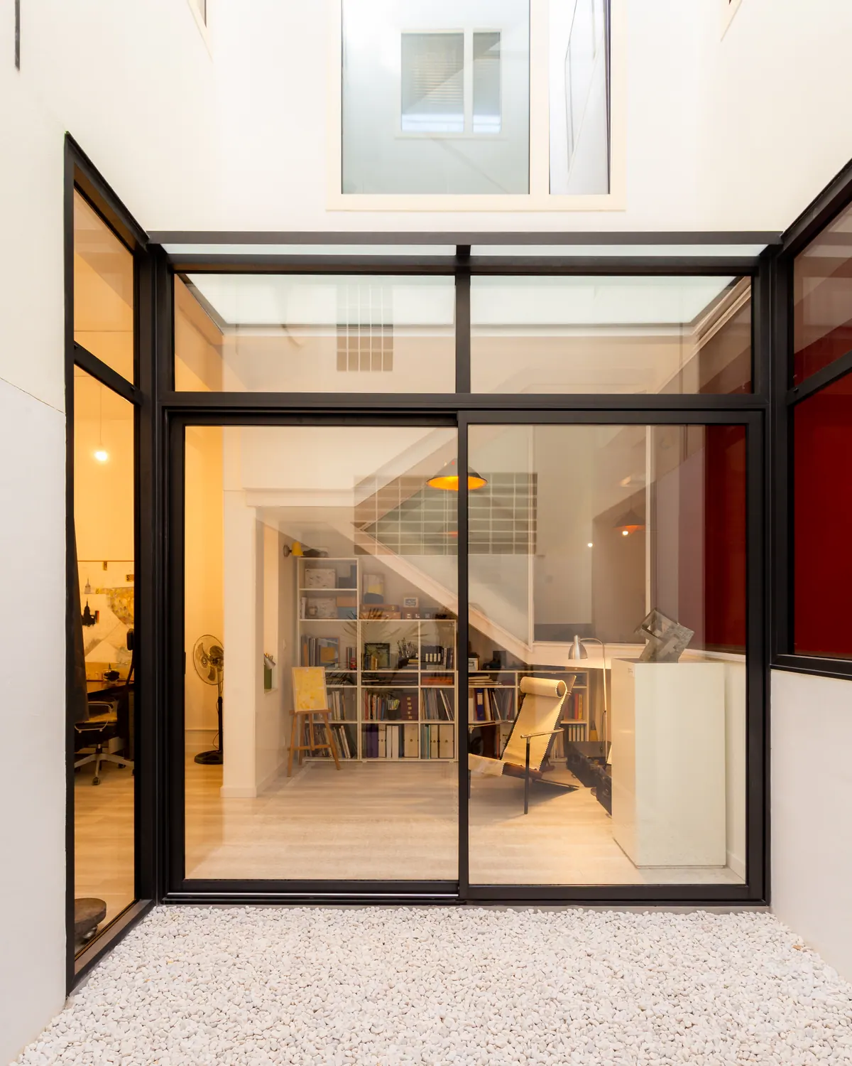 Patio interior cerrado con carpintería de aluminio negro y gran puerta corredera