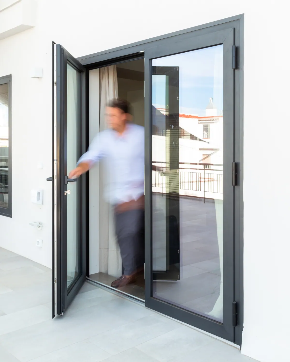 Puerta practicable de aluminio negro abierta a una azotea